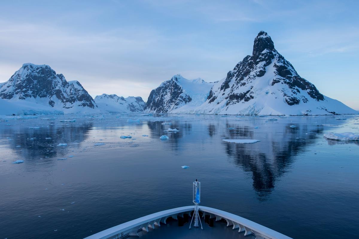 Expedition vessel in Antarctic pack ice with glaciated peaks